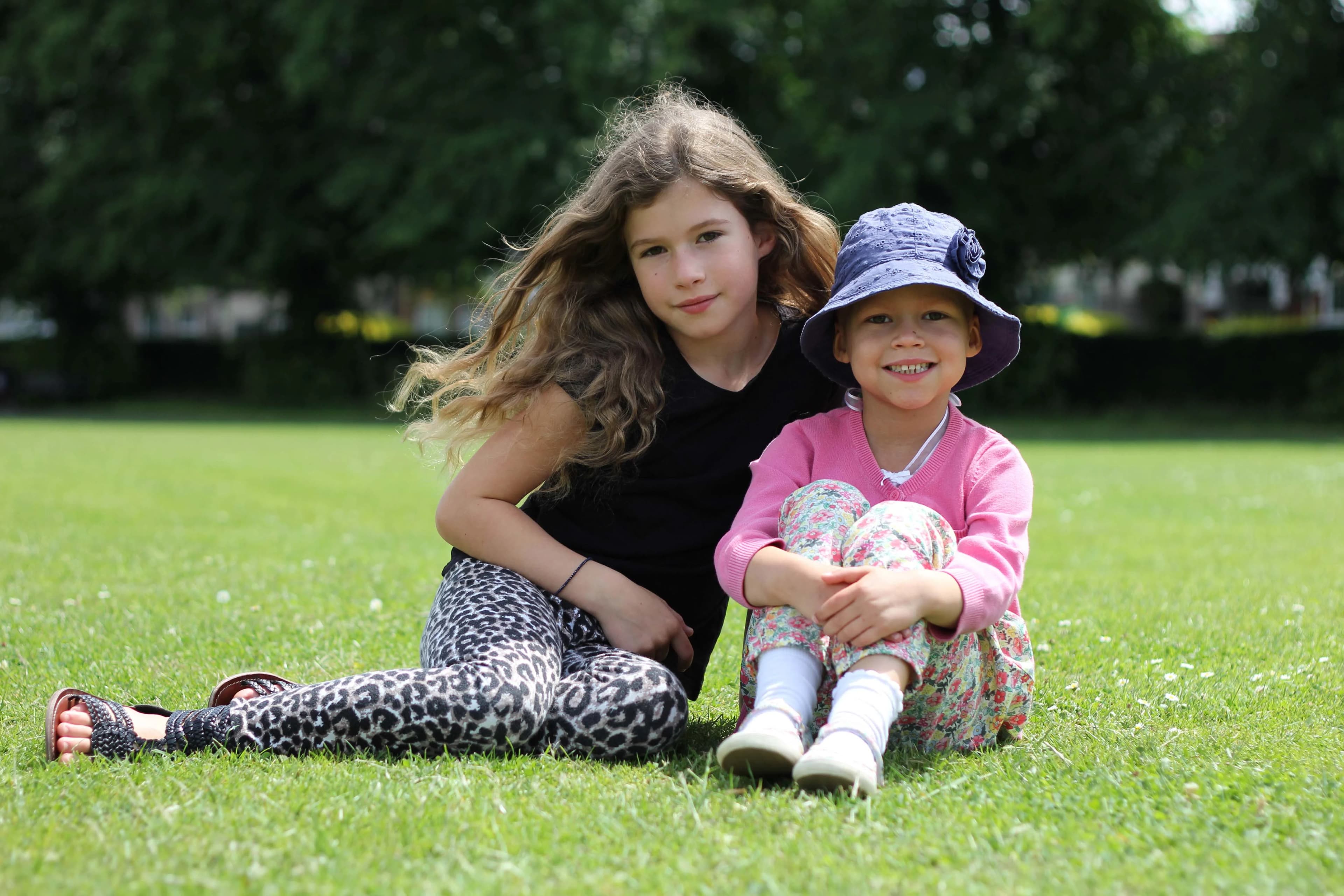 Two young girls sitting together on the grass